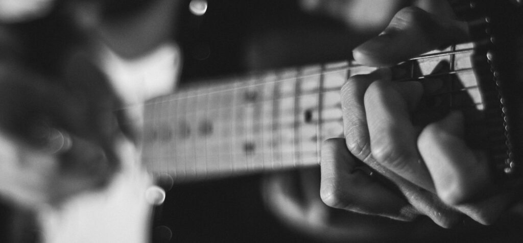 grayscale photo of person playing guitar